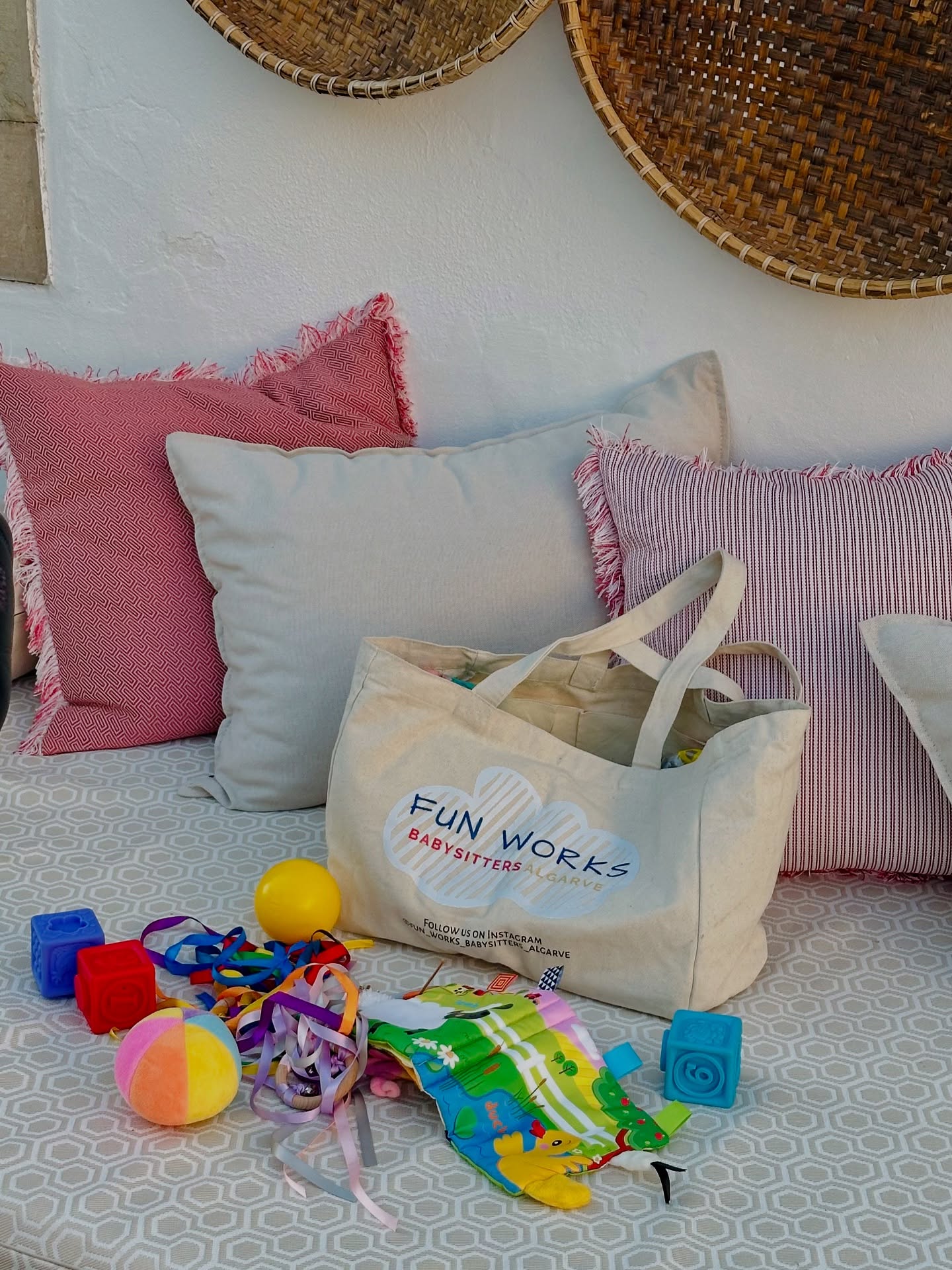 The FunWorks Babysitters canvas activity bag on a villa daybed, with soft blocks, ribbons and a fabric play book beside it